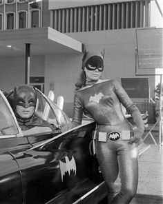 a woman in batman costume standing next to a car