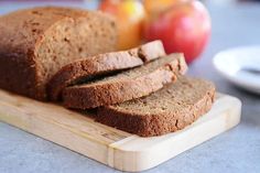 sliced loaf of bread sitting on top of a cutting board next to apples and oranges