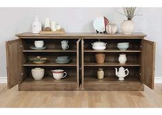 a wooden cabinet filled with dishes and vases