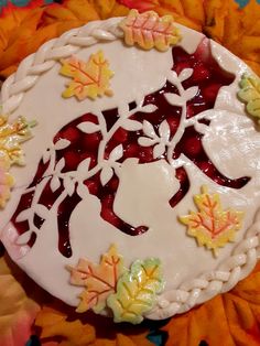 a cake decorated with leaves and icing on top of a tablecloth covered in flowers