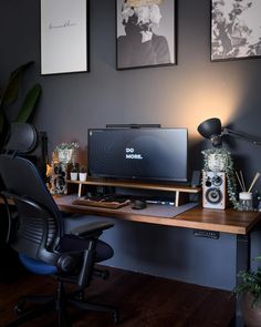 a desk with a monitor, keyboard and speakers on it in front of two framed pictures