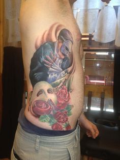 a man with a tattoo on his stomach has a mask and roses around his waist