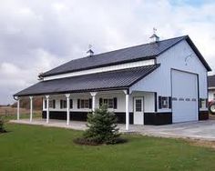 a large white building with a black roof and two cars parked in front of it