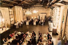 a group of people sitting at tables in a room with chandeliers and windows