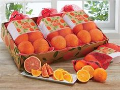 an open box filled with oranges on top of a wooden table next to slices of grapefruit