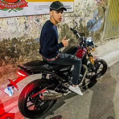 a man riding on the back of a red motorcycle