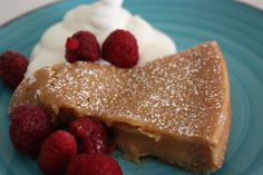 a piece of pie on a blue plate with raspberries and whipped cream