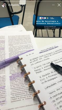 an open book sitting on top of a table next to a pen