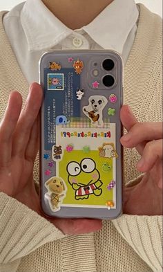 a person holding up a cell phone case with cartoon stickers on the front and back