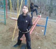 two people standing in front of a swing set with one person on the swingset