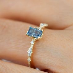 a woman's hand with a ring on it that has an aqua blue stone in the center