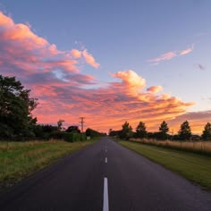 the sun is setting on an empty road