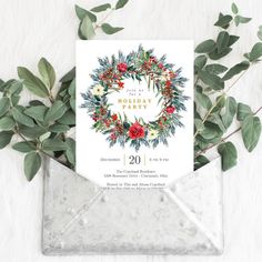 the holiday card is in an envelope surrounded by greenery and foliage, with a white background