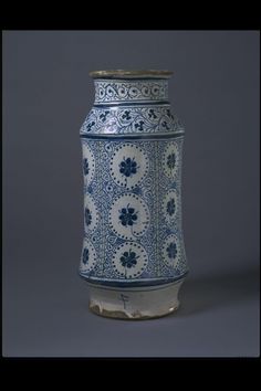 a blue and white vase sitting on top of a gray table next to a wall