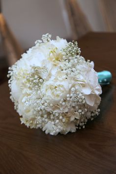 a bouquet of flowers sitting on top of a wooden table next to a cell phone