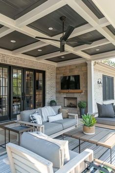 an outdoor living area with couches, chairs and a television mounted on the wall