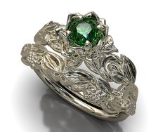 a close up view of a ring with a green stone surrounded by leaves and vines