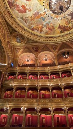 an ornately decorated auditorium with painted ceiling and red seats, is seen from the front