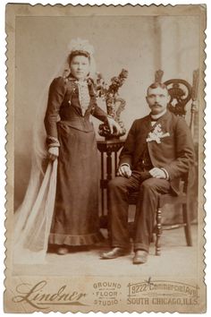 an old photo of two people sitting next to each other on a chair with flowers in their hands