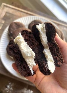 someone is holding two chocolate cookies with white frosting