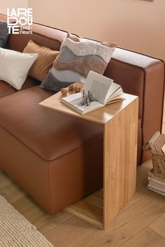 a brown leather couch sitting on top of a hard wood floor next to a wooden table