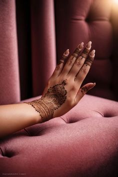 a woman's hand with hennap on it sitting on a pink couch