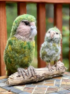 two small birds sitting on top of a piece of wood