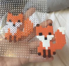 someone is holding two pieces of bead art that look like fox and bear beads