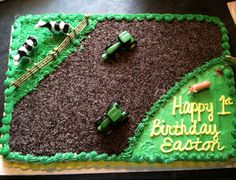 a birthday cake with green frosting and cars on it