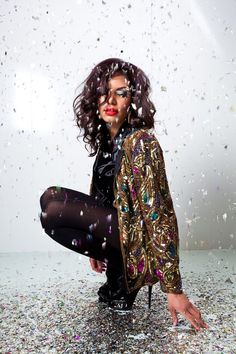 a woman sitting on the ground with confetti all over her face and legs