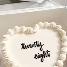 a heart shaped cake with the words twenty eight written on it in black letters and white frosting