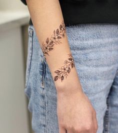 a woman's arm with a tattoo on it that has leaves and flowers on it