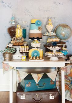 a table topped with lots of luggage and cakes