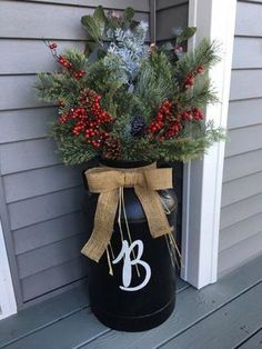 a black bucket with red berries and evergreens in it on the front door sill