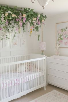 a white crib with flowers hanging from the ceiling