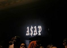 a group of people standing in front of a neon sign that reads asad on it