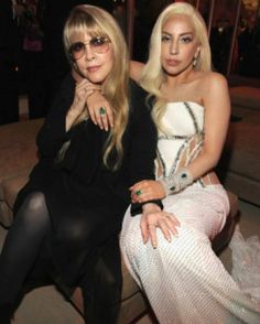 two women sitting next to each other in front of a building with lights on it