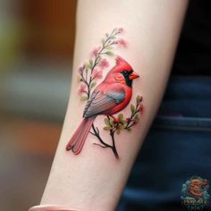 a red bird sitting on top of a tree branch with leaves and flowers around it