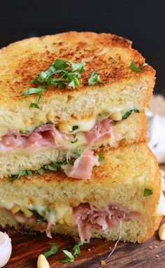 two grilled sandwiches stacked on top of each other with cheese, ham and herbs