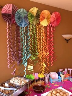 a table topped with lots of desserts and paper umbrellas hanging from the wall