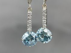 These lovely zircons are bright and bold! The color is cool, luscious sky blue, with plenty of sparkles! The long bar at the center is inlaid with sparkling diamonds, at the very top are the earring wires, hinged lever backs which are brand new, 14K white gold with a simple polished design. These are comfortable to wear and very secure! Metal: 14K White Gold Gem: 2 Blue Zircon totaling 6.81 Carats Gem Measurements: 8.2 mm, Round Accents: 10 Diamonds totaling .10 Carats, F in Color, VS in Clarity White Gold Drop Earrings, Beautiful Tiaras, Edwardian Jewelry, Earring Wires, Cameo Ring, Fabulous Jewelry, Blue Zircon, Gold Drop Earrings, Jewelry Patterns