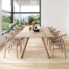 a wooden table with chairs around it in front of a large window that looks out onto the countryside