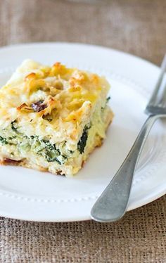 a piece of quiche on a white plate with a silver fork next to it