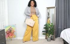 a woman standing in front of a mirror holding a purse and posing for the camera