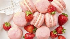 some pink macaroons and strawberries on a white plate