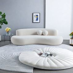 a modern living room with white furniture and flowers in vases on the side table