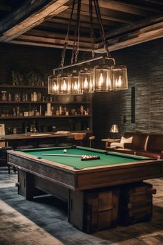 a pool table in the middle of a room with chairs and lights hanging from it