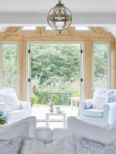 a living room filled with white furniture and lots of windows