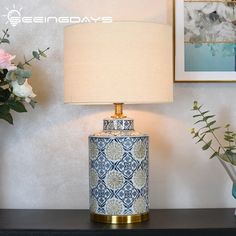 a blue and white lamp sitting on top of a table next to a vase with flowers