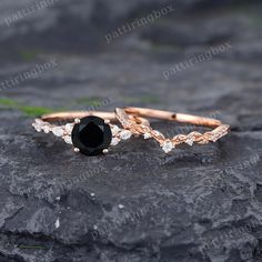 two gold rings with black stones on top of rocks and grass in the foreground